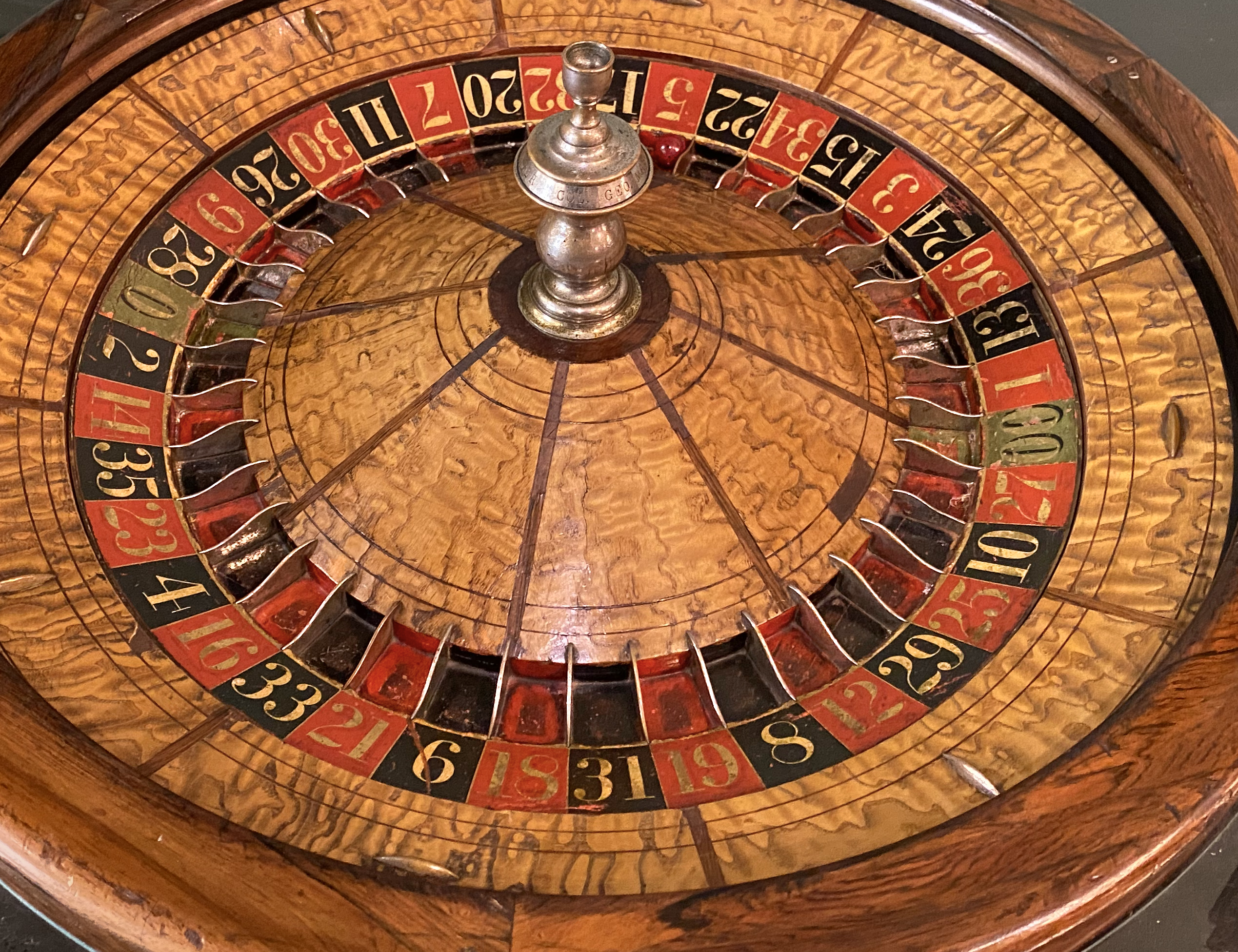 Wooden roulette wheel with alternately red and black numbers 1 through 36 and green numbers 0, and 00.